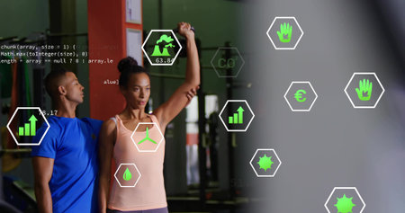 Male trainer assisting woman raising arm at gym, tank, weight racks, red pillar, data overlay....