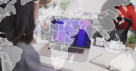 Working coworkers in gray blazer and red top using silver laptop at office, world map overlay....