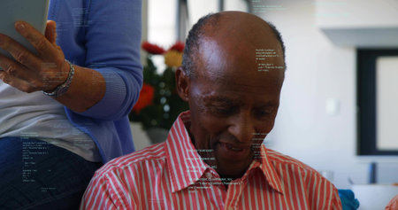 Reading senior man wearing striped red shirt leaning forward in living room, woman holding tablet....