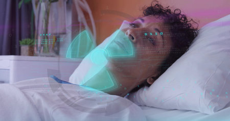 Reclining patient wearing gown on bed in care room, being monitored by cyan HUD fan icon. Woman, adult, healthtech, holographic, projection, medical, ambientの写真素材