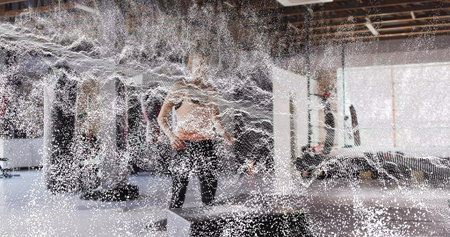 Standing female in sleeveless top and dark leggings in fitness studio, with mist curtain foreground. Gymgoer, athlete, boxing, training, daylight, windows, industrialの写真素材