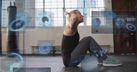 Performing woman in athletic wear doing sit-ups on rubber floor with punching bag and HUD overlays....