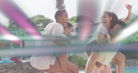 Laughing four adults giving piggyback rides at backyard pool by palm, in swimwear with lens-flare....