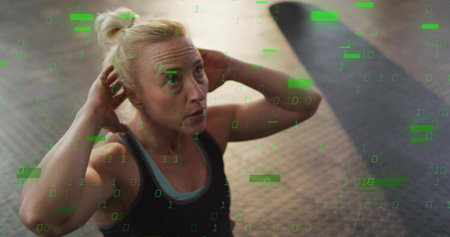 Doing crunch, fit woman with hands-behind-head on rubber floor with green overlay in athletic wear....