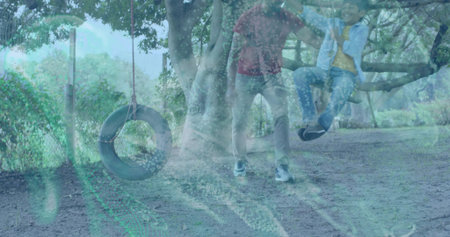Standing man in maroon shirt watching boy in blue jacket on low branch, tire swing. Guardian, kid,...