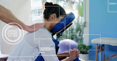 Receiving woman resting face in blue massage chair in clinic, therapist pressing back with overlays. Client, wellness, therapy, bodywork, seating, daylight, windowの写真素材