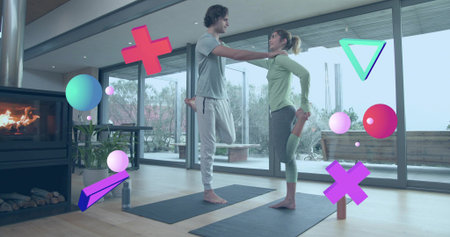 Practicing two women balancing on mats in living room, in athletic wear with floating AR shapes....