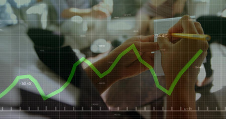 Writing hands in dark sleeve, pencil on spiral-pad at table, green-line-chart overlay, copy space. Planning, collaboration, discussion, data, graph, strategy, growthの写真素材