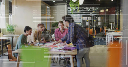 Pointing woman in dark jacket leading team around table in office, with laptop and overlays....