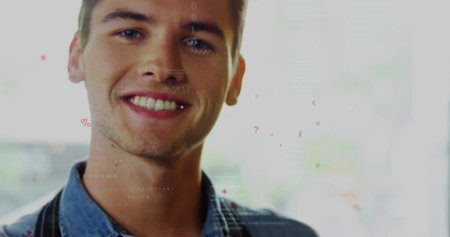 Smiling male barista wearing denim shirt and apron straps at bright window, with data overlays....