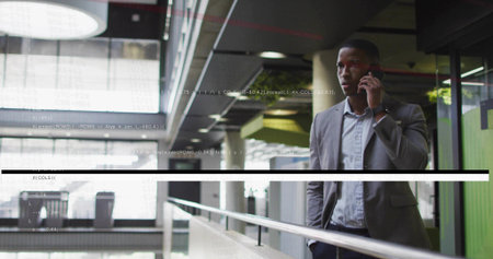 Talking on smartphone, man in business attire pausing at glass railing in atrium, copy space....