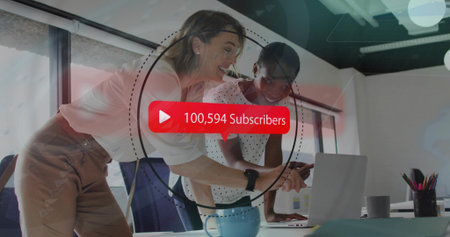 Leaning women in business attire pointing, smiling at laptop in office with red subscriber overlay....