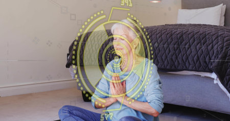 Sitting senior wearing blue shirt, jeans praying at chest on dark mat beside bed. Meditation, calm,...