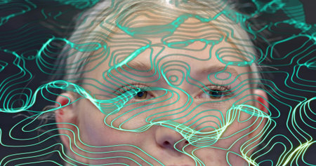Showing adult female face with glowing teal contour lines flowing across features in studio....
