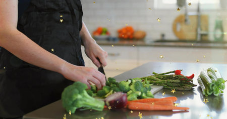 Chopping woman in black apron prepping veggies on steel counter with knife, broccoli, copy space....