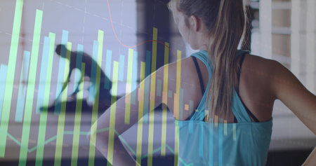Standing woman in teal tank observing gym with silhouette left, displaying data overlay, copy space....