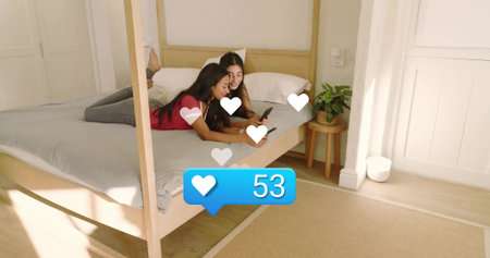 Lying women in red and dark tops scrolling phones in bedroom showing heart icons 53 notification....