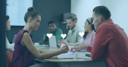 Holding pen, female in plum blouse reaching for coworker across table, heart icons, copy space....