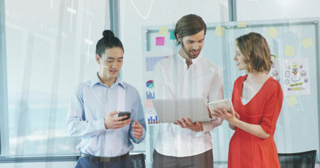 Presenting woman in red dress with team discussing laptop tablet phone in office near whiteboard....
