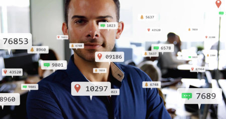 Standing man in blue shirt crossing arms, facing camera at open-plan office with digital overlays....