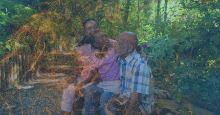 Sitting senior woman, child, senior man sharing moment on bench in wooded park, golden overlay. Family, outdoor, sunlight, texture, garden, warmth, harmonyの写真素材