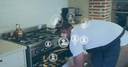 Mid-adult man wearing white-tee striped-apron removing tray from oven at home with mitt user-icons....