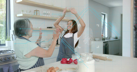 High-fiving mother and teen wearing aprons, preparing dough in home kitchen with flour jar. Baking,...