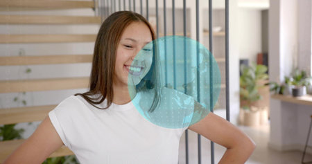 Smiling teen wearing white T-shirt standing at home, showing staircase. Girl, plants, stairs,...