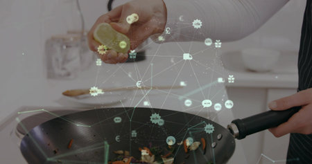 Squeezing lemon, home cook wearing apron adding juice to black wok in kitchen, with digital overlay....