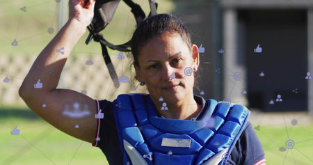 Holding helmet aloft, catcher posing on field, with blue chest protector and fence overlays. Softball, outdoor, outfield, grass, athlete, sunlit, dugoutの写真素材
