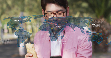 Standing Asian man in pink blazer holding wrap, checking smartphone on park walkway with AR overlay....