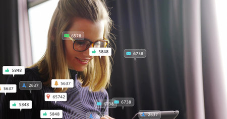 Holding adult woman wearing glasses and dark ribbed top using tablet at office with alerts. Female,...