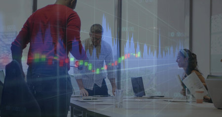 Reviewing market overlay, colleagues in red sweater leaning in glass office with laptops and docs....