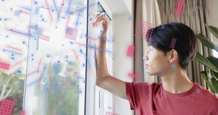 Tracing teen in red tee at home drawing blue-red overlays on glass with marker, copy space. Window,...