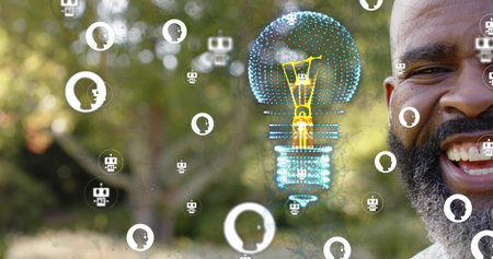Smiling bearded man showing teeth in park with pale shirt and holographic lightbulb, copy space....