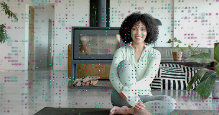 Sitting woman in mint-green top, gray leggings on dark mat by glass fireplace with stacked logs....