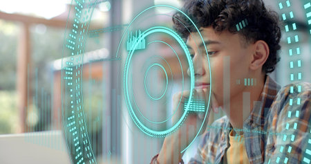 Studying male in plaid overshirt yellow tee, viewing teal HUD above laptop near window, copy space. Augmented, reality, interface, focus, concentration, homeoffice, daylightの写真素材