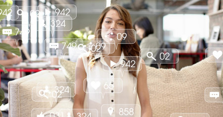Sitting woman presenting on sofa in office lounge, wearing sleeveless white top with UI overlays....