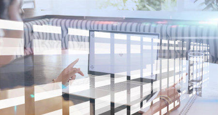 Pointing adult Indian woman wearing dark top tapping laptop screen at cafe booth, blinds reflection....