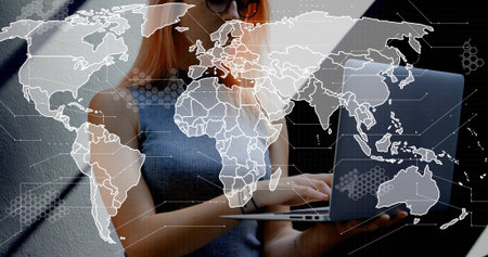 Typing woman in sleeveless ribbed top shades holding silver laptop at gray wall with digital map....