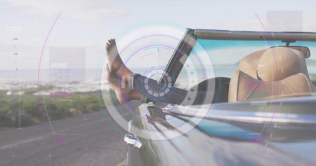 Reclining passenger resting bare feet from convertible on coast road showing cuffed denim and HUD. Car, travel, leisure, outdoor, scenic, leather, luxuryの写真素材