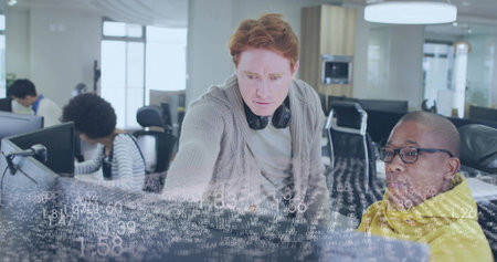 Leaning red-haired dev pointing at screen in office showing data overlay, headphones, yellow hoodie....