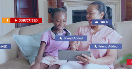Smiling grandma and grandkid using tablet on sofa in living-room in pink-purple headset....