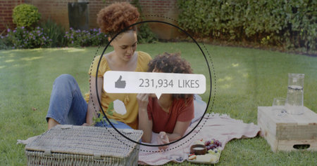 Sitting two women wearing mustard red tops on blanket in garden with basket, 231934 LIKES overlay....