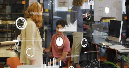 Listening man in pink T-shirt talking with woman in light blazer at office, glass partition charts....