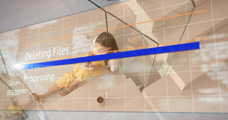 Sitting woman wearing yellow overalls, white headphones, using phone near progress overlay in lobby....