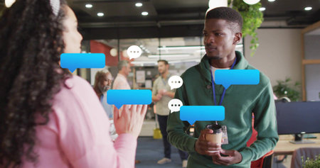 Holding coffee cup, green-sweater man with badge talking to peer at office chat overlay, copy space....