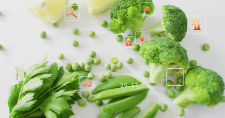 Showing assorted greens on white tabletop with broccoli, peas, pods, parsley, lemon. Produce,...