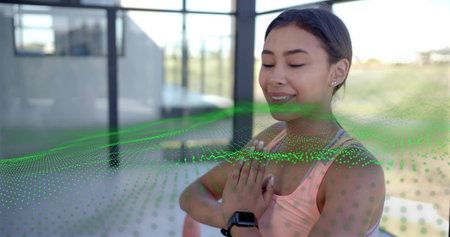 Centering woman in pink top pressing palms in glass studio, with smartwatch and green overlay....