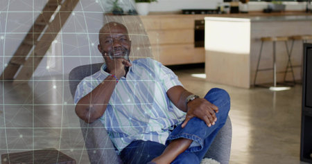 Sitting senior man wearing striped shirt and jeans in open-plan home, with armchair, grid overlay....